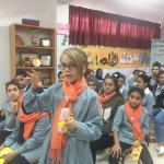 Photo of girls in a classroom. They are wearing orange scarfs.