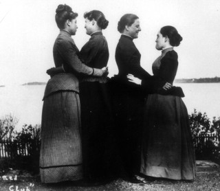 Women in early 19th century dresses embrace in a black and white painting.
